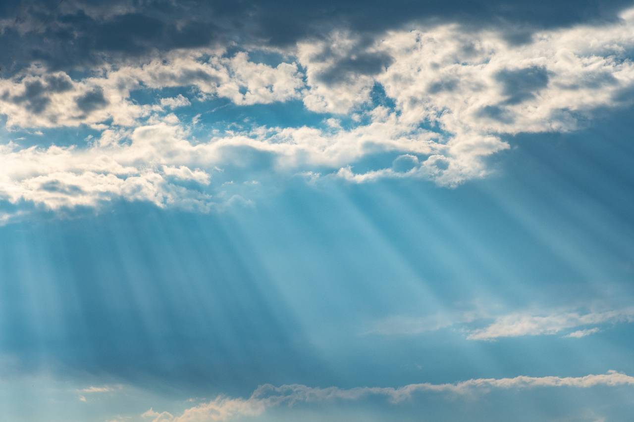 Rays of sunshine breaking through the clouds in a blue sky