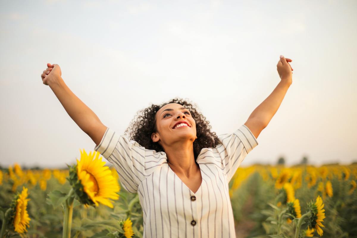Woman making a victory pose in a sunflower field