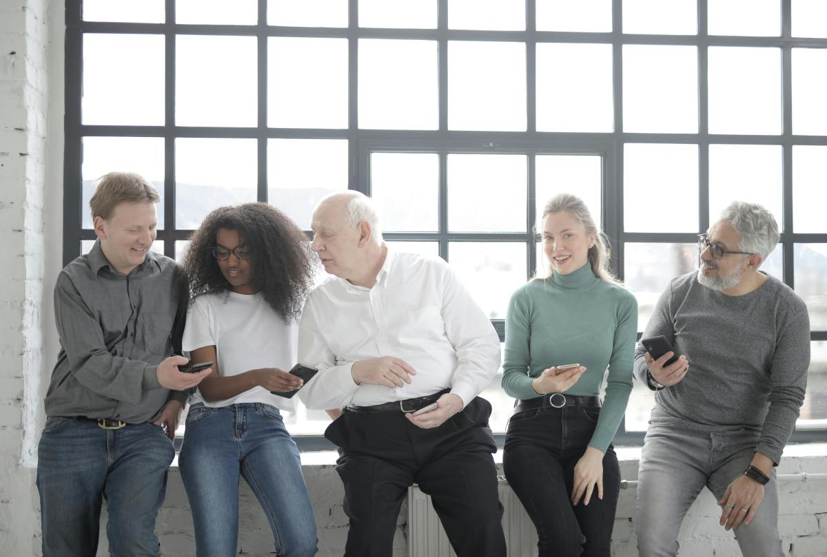 Group of people on their phones while seated by a window
