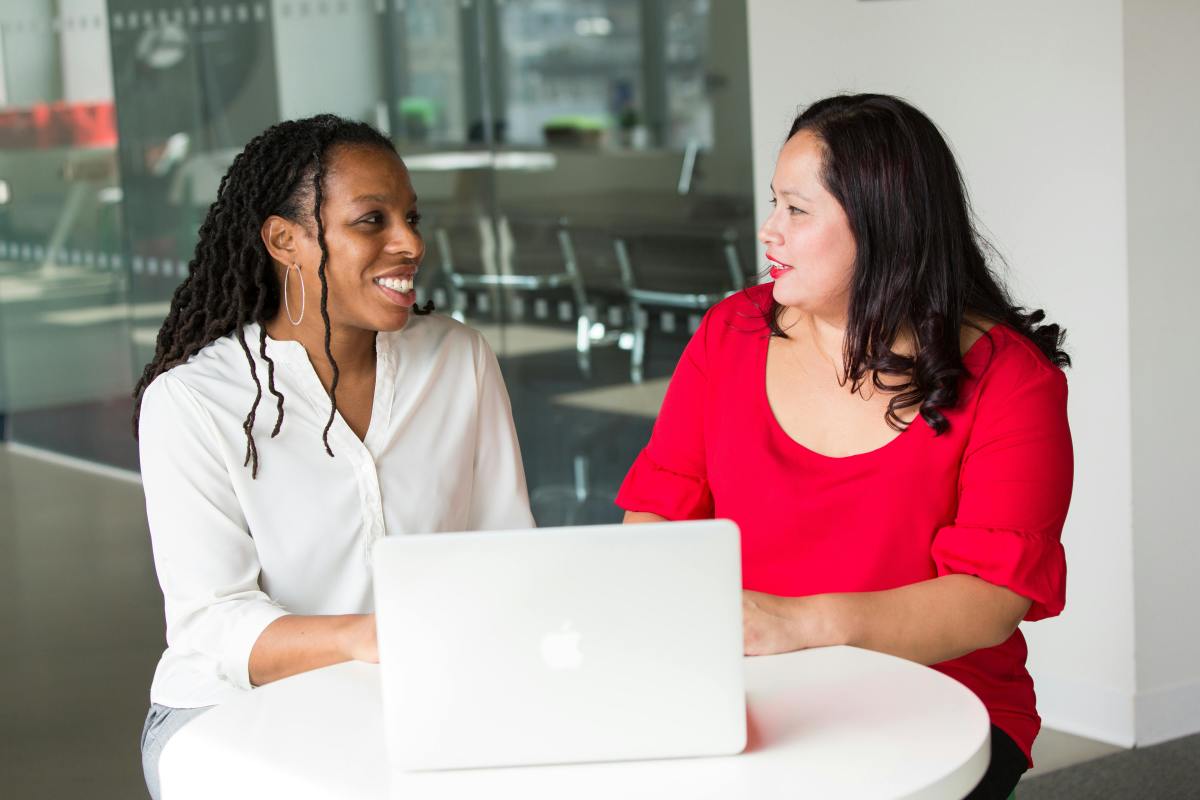 Woman in red shirt sitting beside a woman in a white shirt