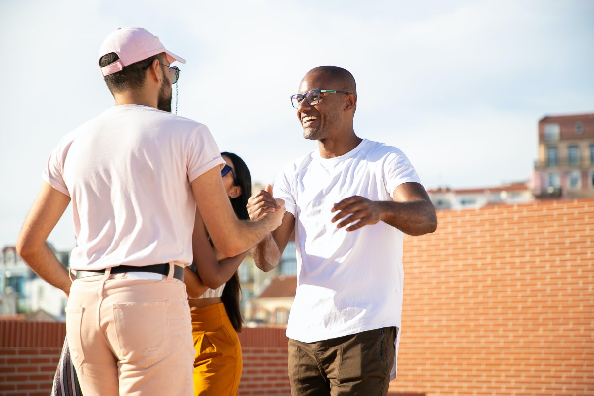Cheerful men shaking hands on urban building terrace
