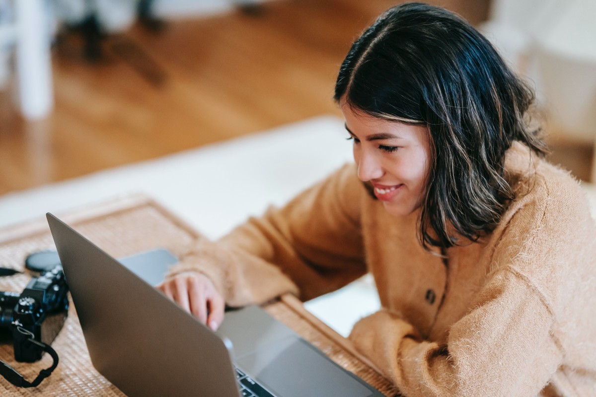 Cheerful female photographer using laptop at home