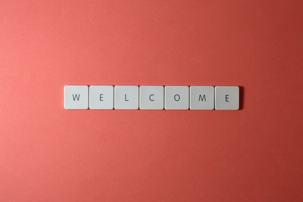 Close-up shot of keys on a red surface that spell "Welcome"