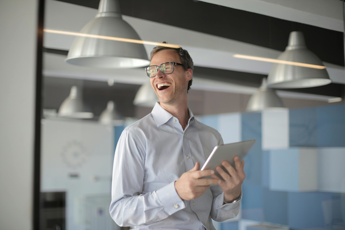 Laughing Man in White Shirt Carrying a Tablet