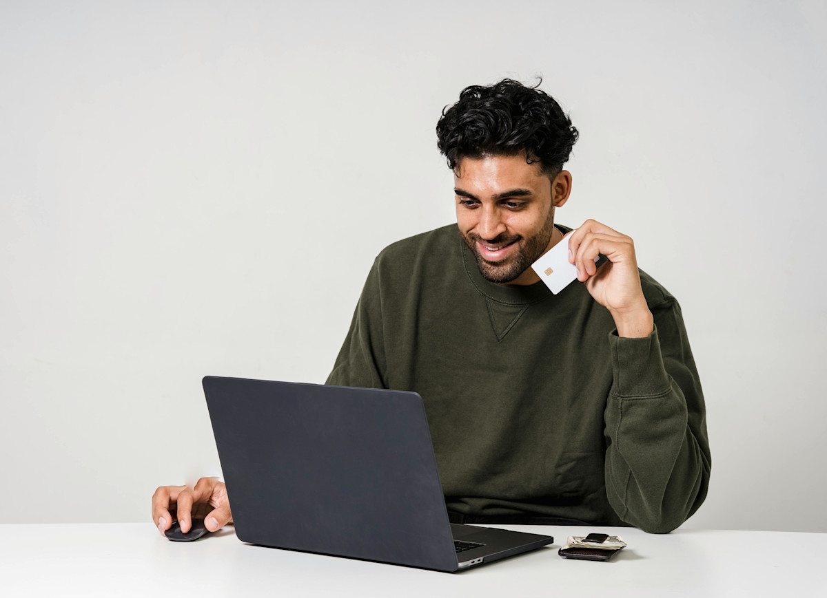 Man Holding A Credit Card and Using a Laptop