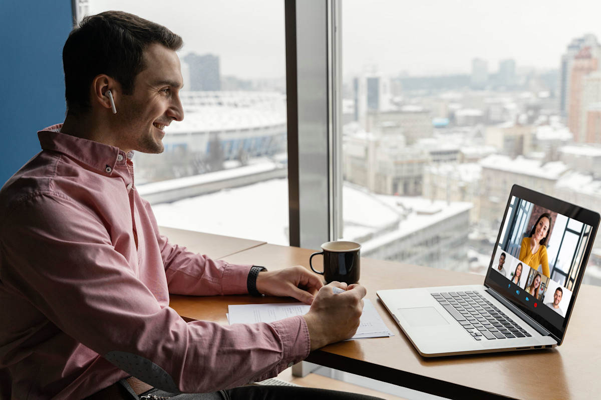 Side view of man having an online video call with coworkers
